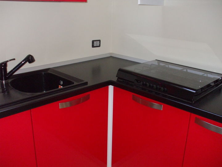 Cucina angolare rosso lucido perfettamente inserita nel contesto abitativo.