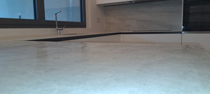 Cucina bianca lucida ad angolo con top nero e colonna forno/microonde a scomparsa.